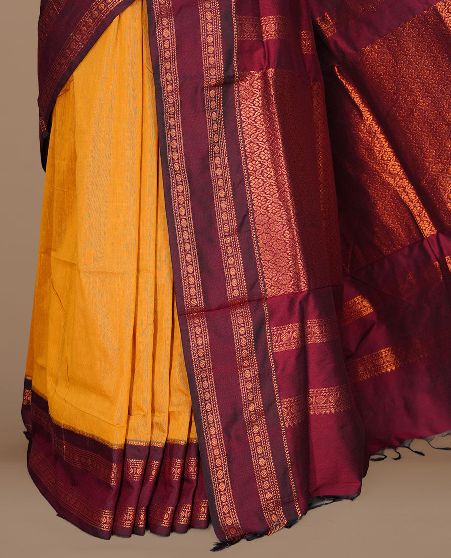 Mustard colour kalyani cotton saree featuring gold zari motifs on body, complemented by contrast maroon color with copper zari pattern border , paired with mtaching blouse piece.