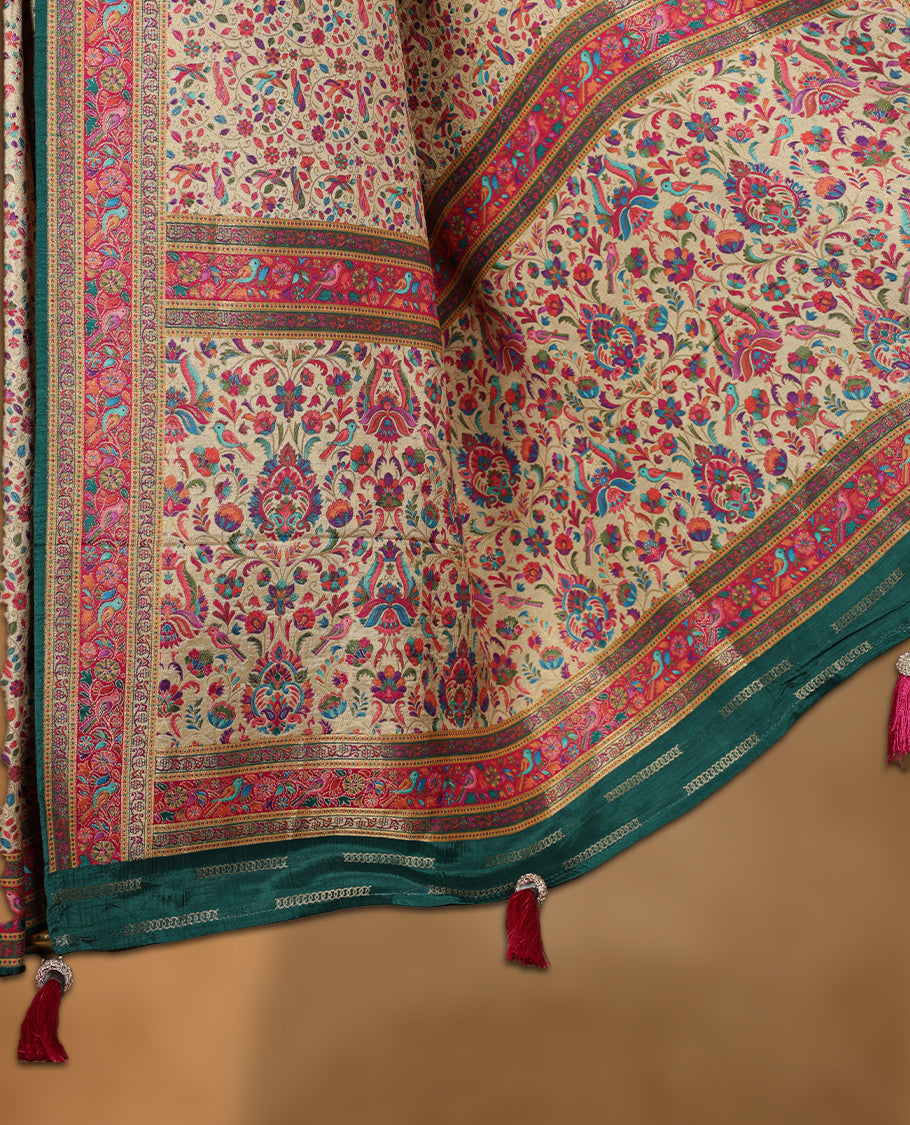 Beige colour Pashmina silk saree intricately woven with all over multicolour floral and paisley vines, accented by a rich pink and green zari border with bird motifs and a coordinated grand pallu, paired with a contrasting matching blouse piece.