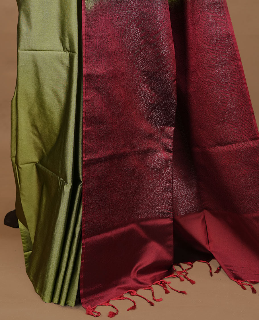 Olive colour soft silk saree features a sleek borderless design with intricate antique zari motifs, flowing into a striking contrast red pallu and a matching blouse piece.