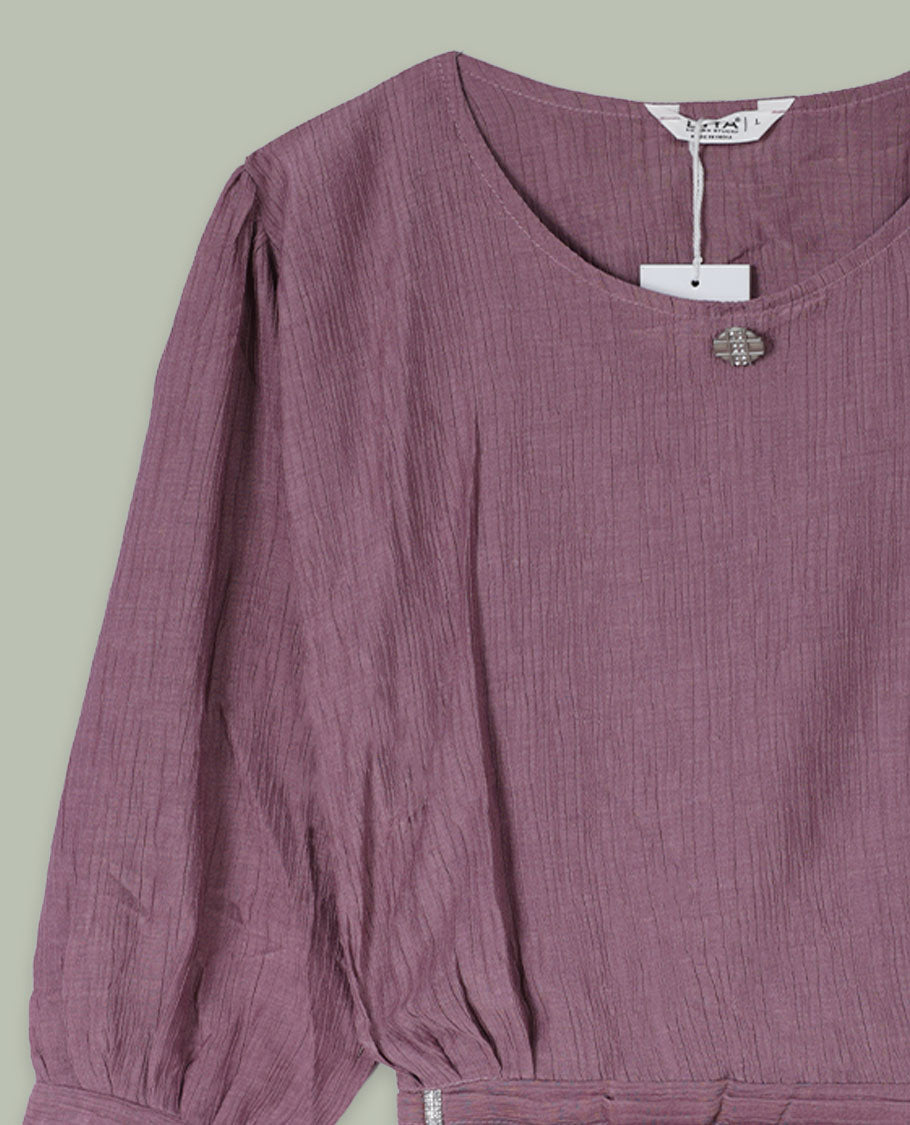 Dusty mauve three-quarter sleeve top with round neckline, metal button detail at the neck, and a pleated waistband accented with slim metallic trims.