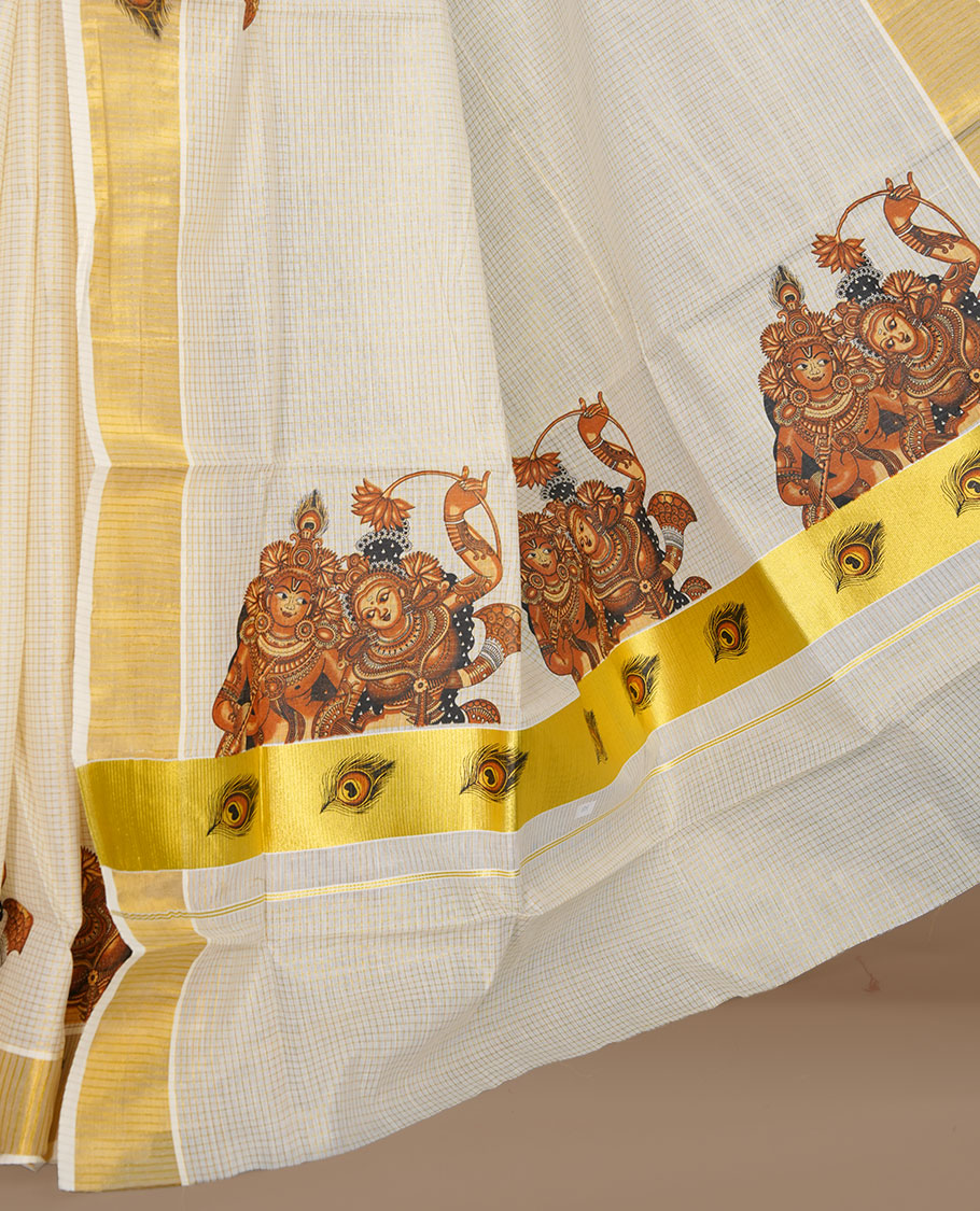 Off white color kerala cotton saree featuring gold zari check on body, complemented by, gold zari with krishna & peacock leaf printed border, paired with matching blouse piece.