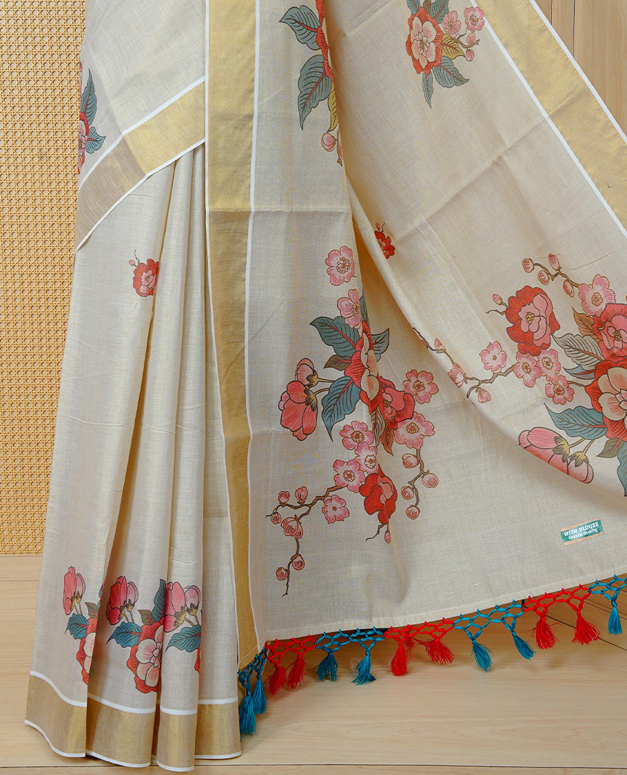 Cream Colour Tissue Kerala Saree Featuring Vibrant Digital Floral Prints Printed On Body & Pallu, Beautifully Enhanced With A Classic Gold Zari Border And Red & Blue Tassels. Paired With A Matching Blouse Piece.