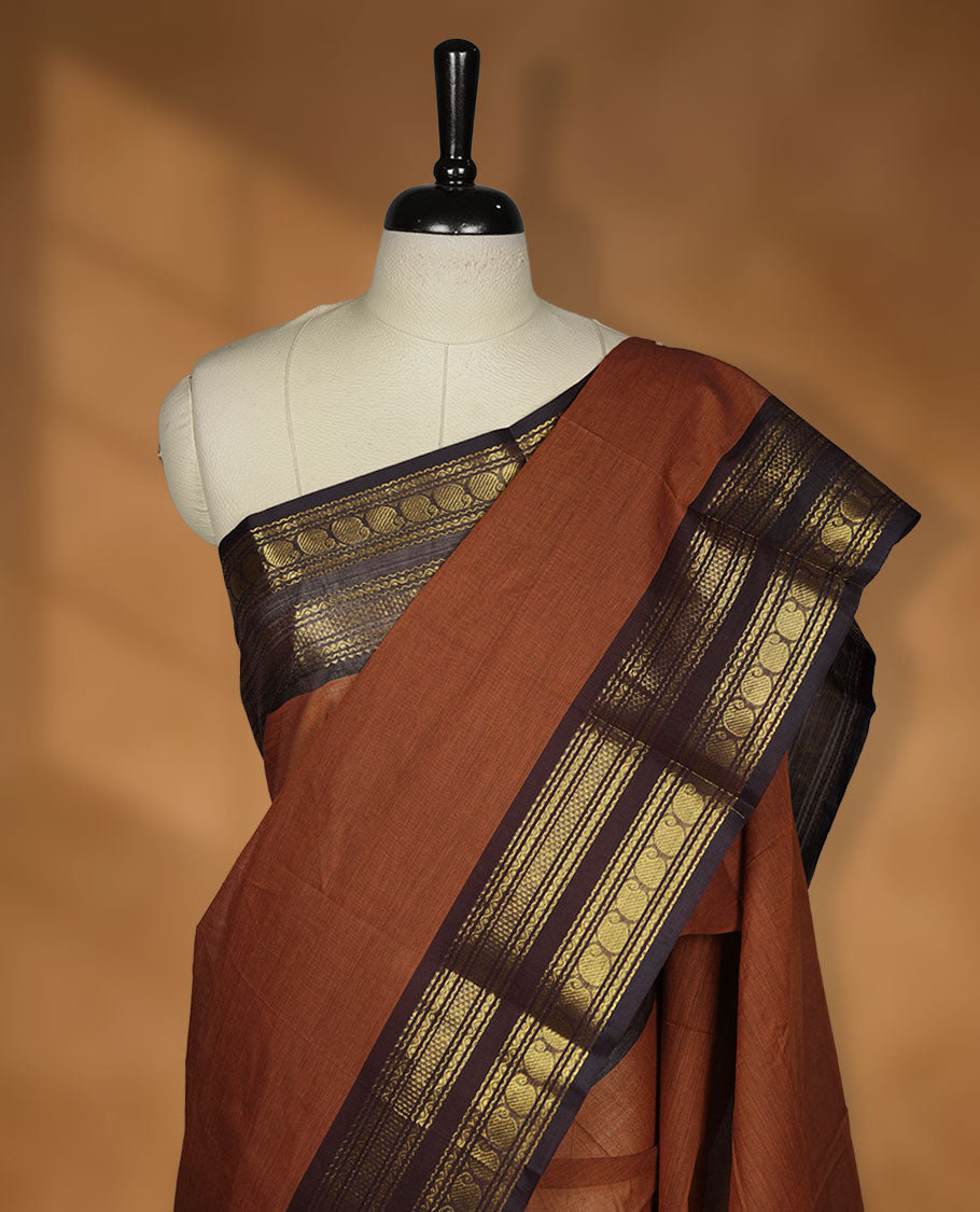 Brown colour chettinad cotton saree featuring plain body, contrast Deep purple colour with traditional gold zari border paired with matching blouse.