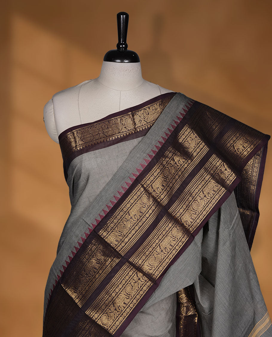 Grey colour chettinad cotton saree featuring plain body, paired with a black colour traditional gold zari border paired with matching blouse.