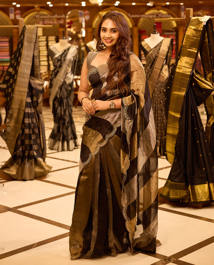 Antique gold and black pure Banaras tissue organza designer saree featuring a vertical black tissue pallu and shoulder panel, a plain antique gold body, and a delicate scalloped embellished border, paired with a matching designer blouse.