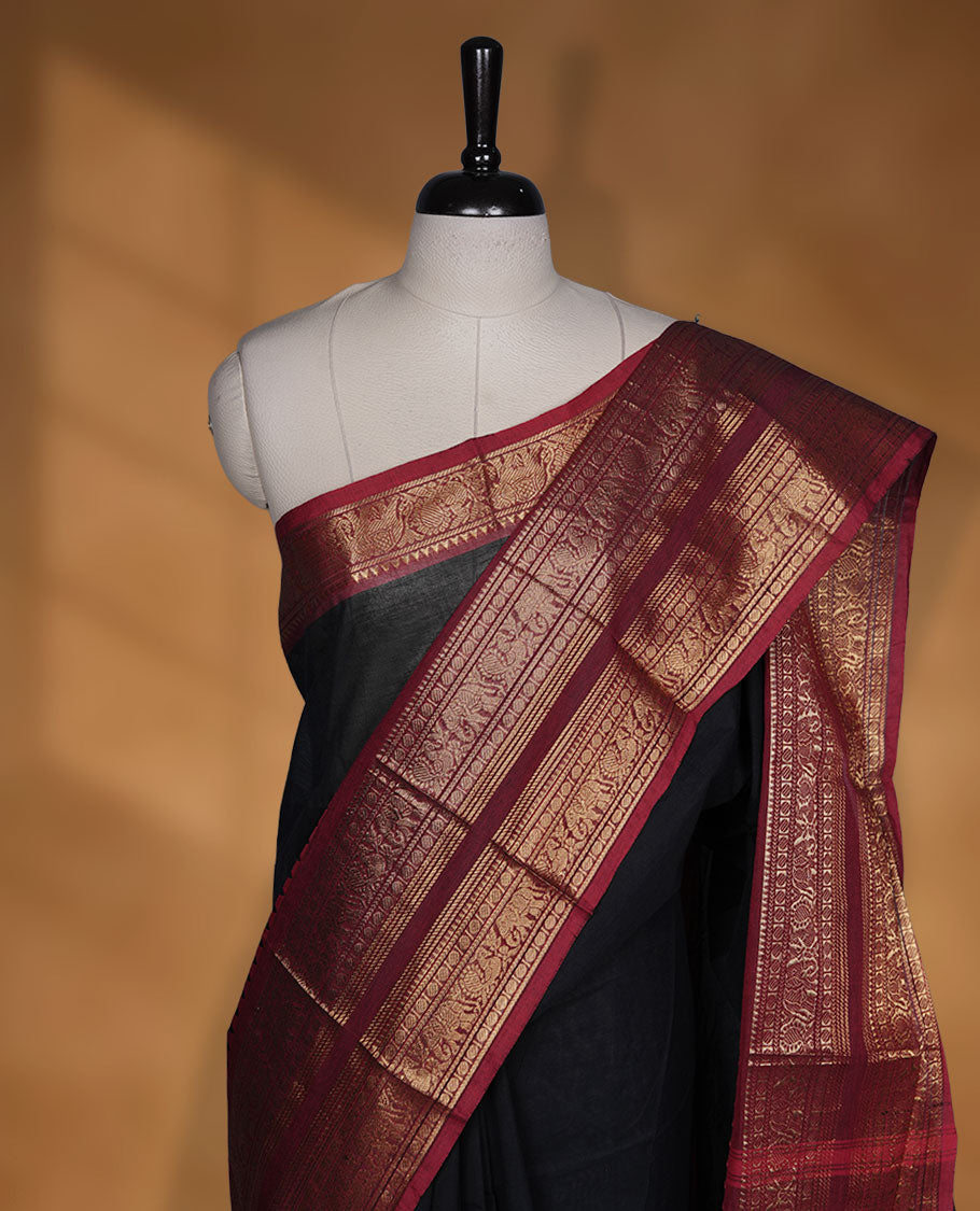 Black colour chettinad cotton saree featuring plain body, contrast maroon colour with traditional gold zari border paired with matching blouse.