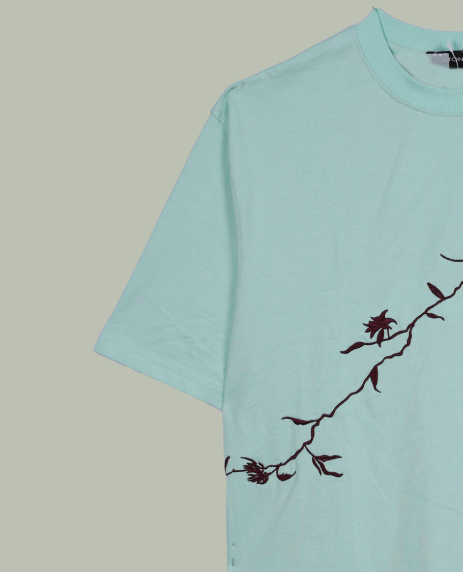 Sky blue colour T shirt featuring intricate wine coloured embroidery on the front and back, designed with a classic round neck and short sleeves & it offers a stylish and comfortable everyday look.