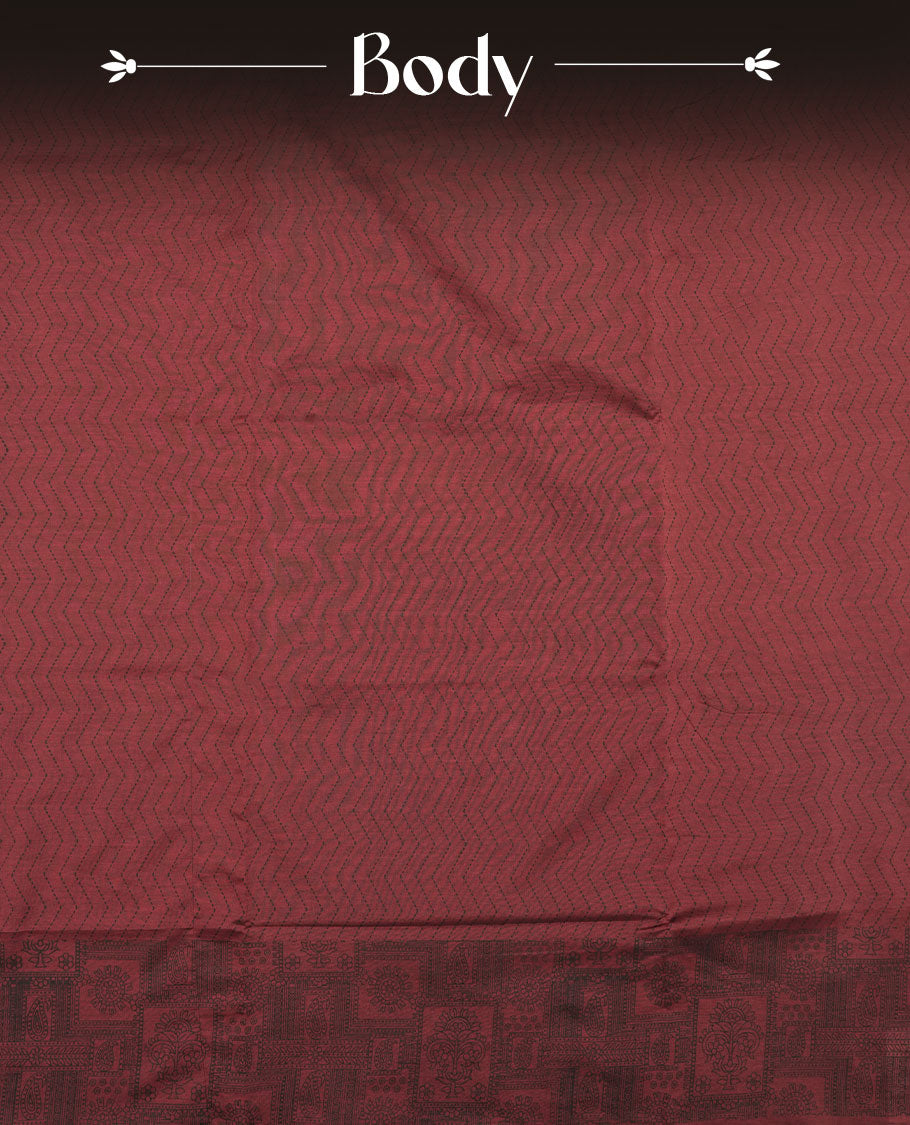 Deep Maroon colour poly cotton saree with black zigzag line pattern on the body, paired with a matching pallu featuring black chevron lines and panelled floral‑paisley design, and a coordinated all‑over floral paisley patch‑style printed blouse piece.