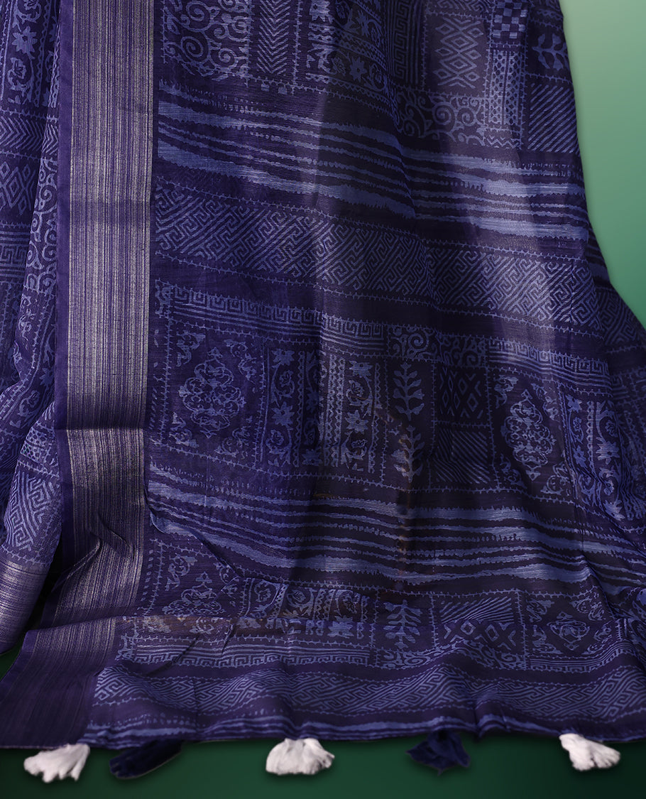 Blue colour saree featuring intricate woven geometric and floral patterns across the body and pallu, highlighted with a subtle striped border and tassels, paired with a matching blouse