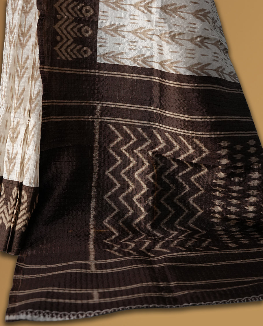 Classic off white colour saree adorned with intricate brown tribal motifs and rich woven patterns on the pallu and border & Paired with matching blouse.