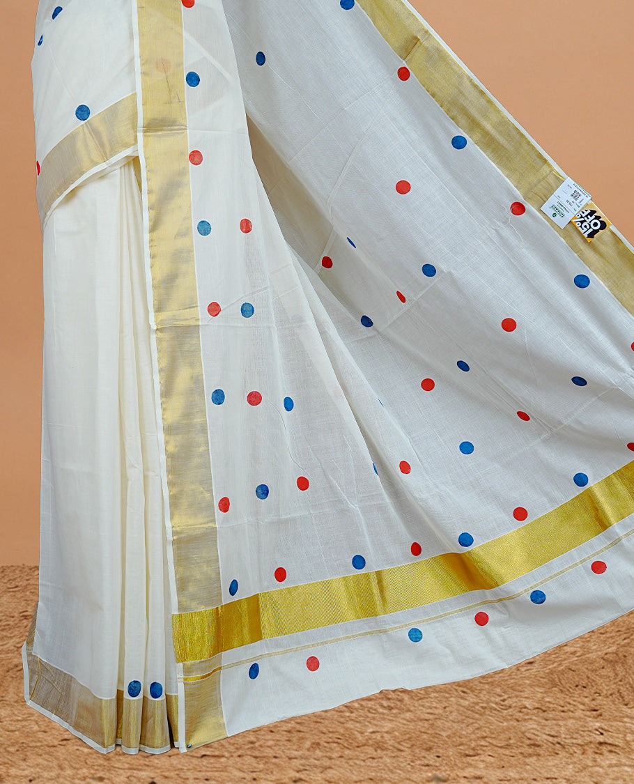 Cream Colour cotton Kerala Saree Featuring Multicolour Dot Prints On The Body, Complemented By A Traditional Gold Zari Border, Paired With A Matching Blouse Piece.