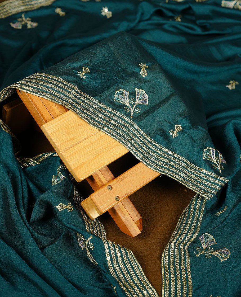 pastel teal colour olive colour churidar material with subtle mirror and thread embroidery, finished with delicate border detailing and paired with a matching plain bottom and dupatta.