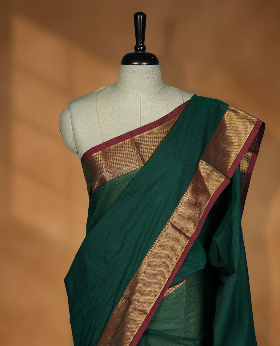Dark green colour chettinad cotton saree featuring elegant plain body highlighting contrast maroon colour colour with gold zari traditional border, pallu and paired with matching blouse piece.