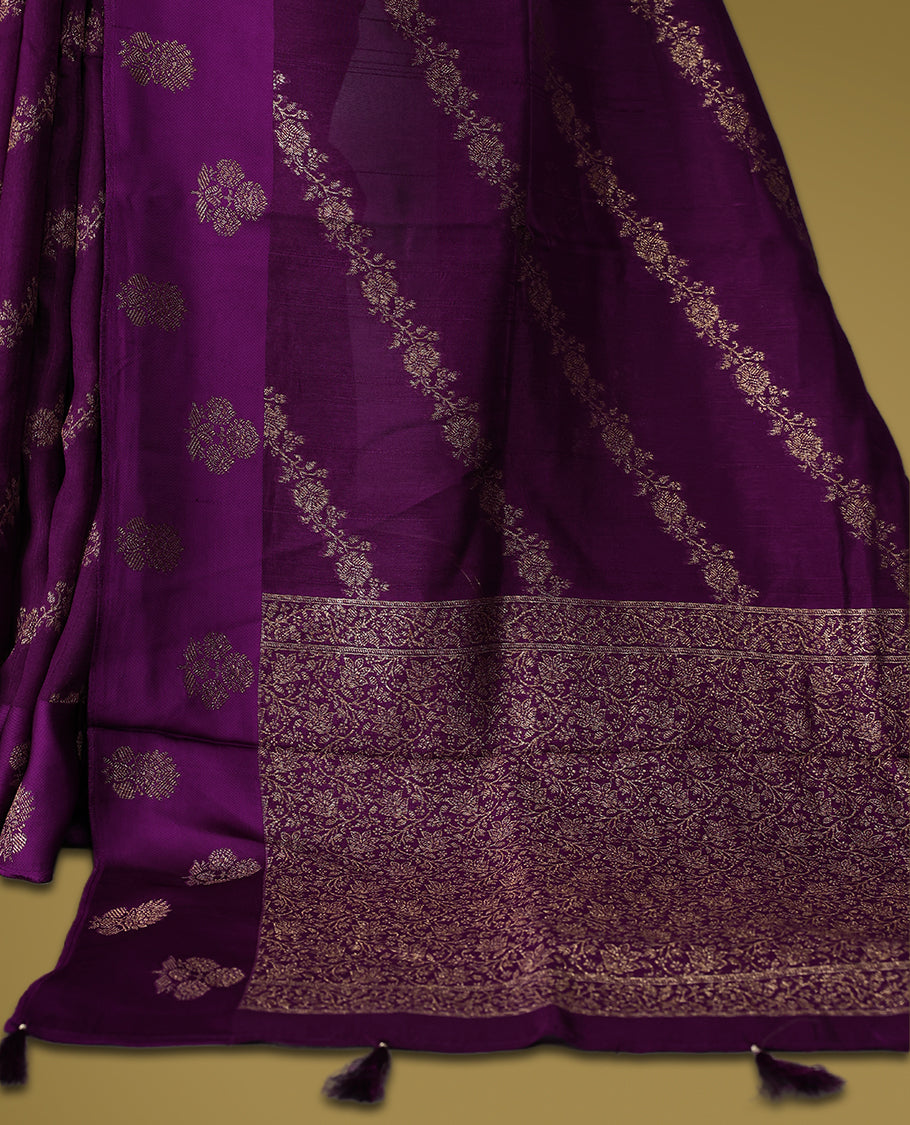 Deep purple semi Banaras tussar saree adorned with golden floral motifs in diagonal patterns across the body and a finely woven zari border, finished with a rich golden pallu, paired with a matching blouse.