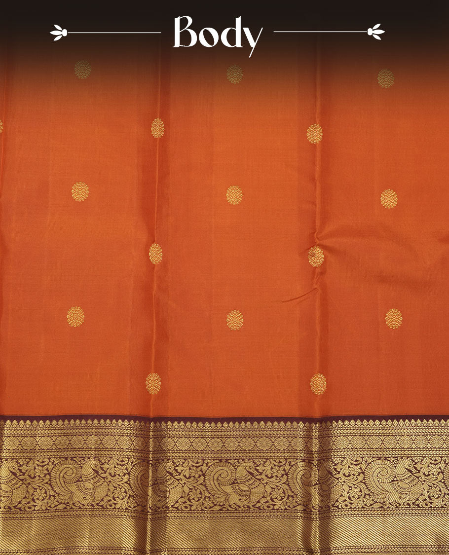 Rust orange colour pure traditional Kancheepuram silk saree adorned with gold zari motifs across the body, featuring elegant contrast Chocolate colour traditional borders, beautifully paired with a matching blouse piece.