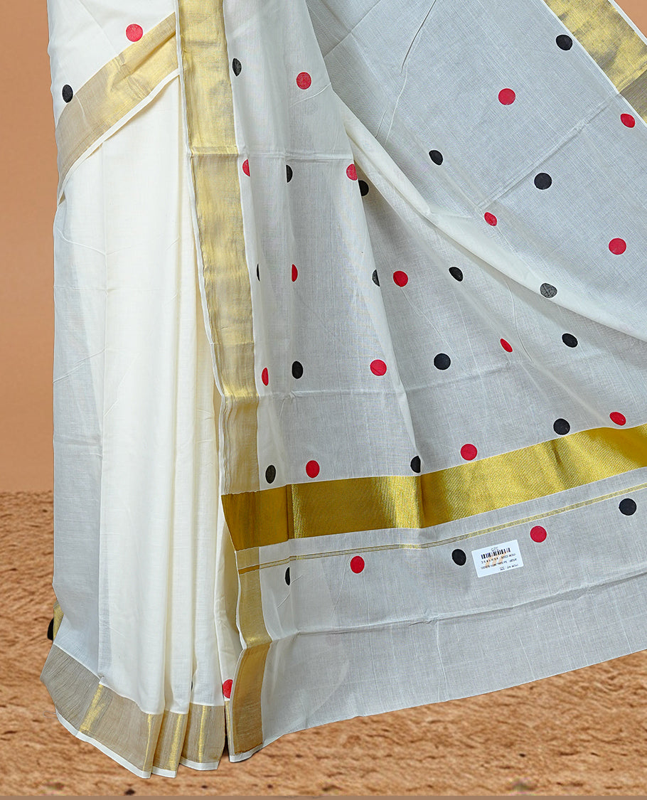 Cream Colour cotton Kerala Saree Featuring Black & Red Dot Prints On The Body, Complemented By A Traditional Gold Zari Border, Paired With A Matching Blouse Piece.
