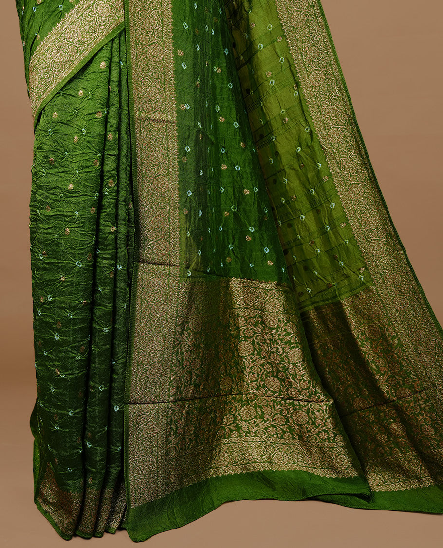 Green colour Banarasi Bandhani silk saree featuring intricate antique zari circle Buttas across the body, complemented by an elegant antique zari border. Comes paired with a matching blouse piece