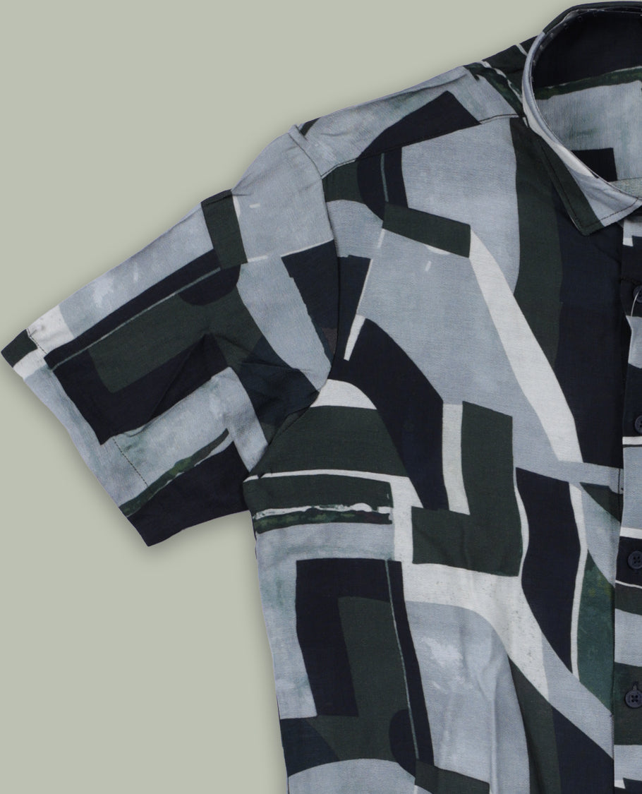 Dark green colour shirt featuring bold abstract geometric prints in shades of black, white, and grey & Designed with a classic collar and short sleeves, it offers a trendy, artistic look perfect for casual outings.