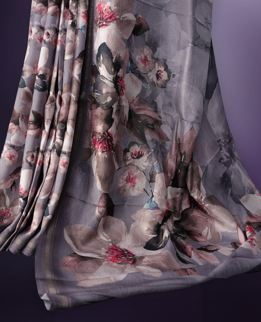 Grey colour saree adorned with elegant floral prints on the body, enhanced with a subtle matching border, complemented by a beautifully printed pallu featuring blooming flowers, and paired with a matching blouse.