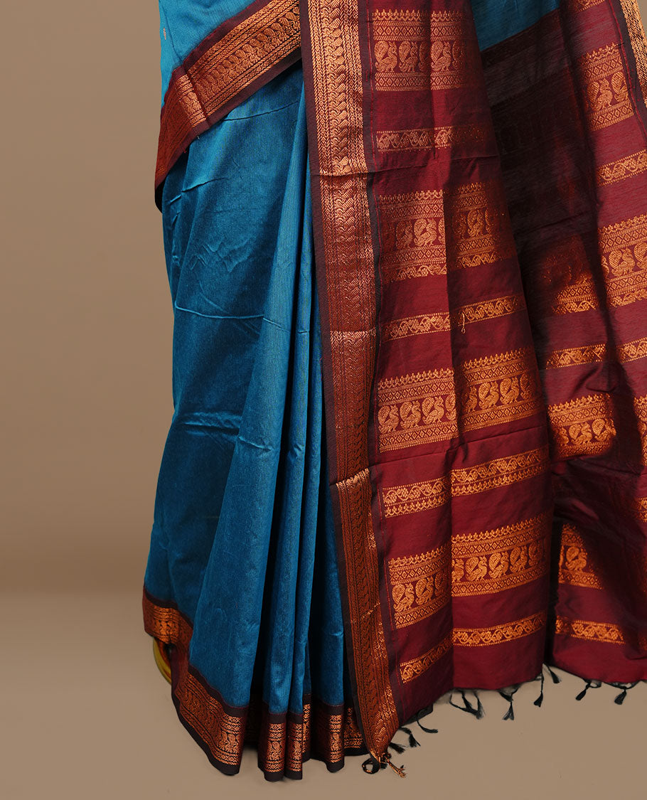 Blue colour kalyani cotton saree featuring antique zari motifs on body, complemented by Maroon colour with Antique zari border, paired with matching blouse piece.