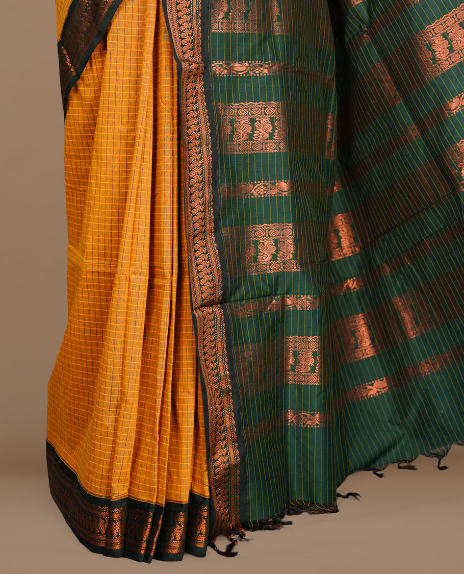 Mustard colour kalyani cotton saree featuring gold zari motifs on body, complemented by contrast green color with copper zari pattern border , paired with matching blouse piece.
