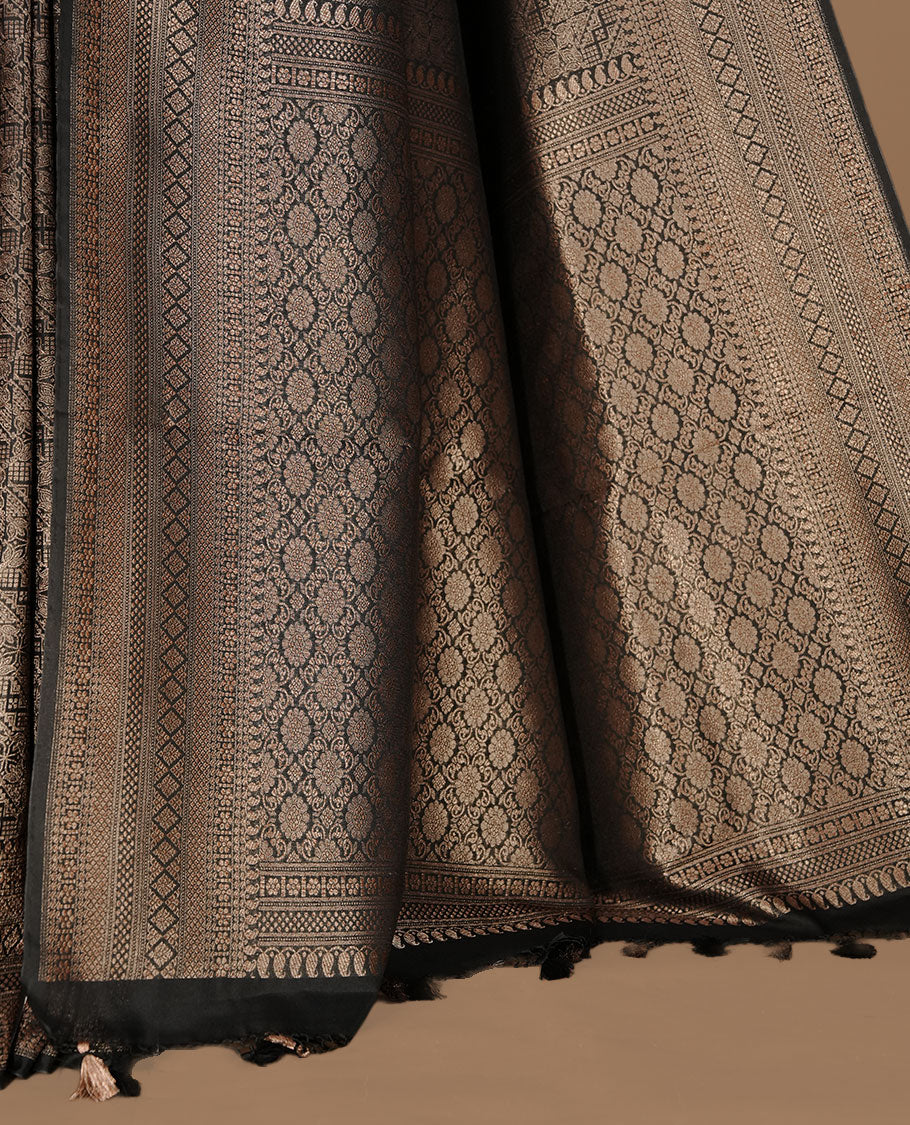 Black colour semi banaras katan saree featuring Gold zari Pattern across body, complemented by self colour with zari border, paired with matching blouse piece.
