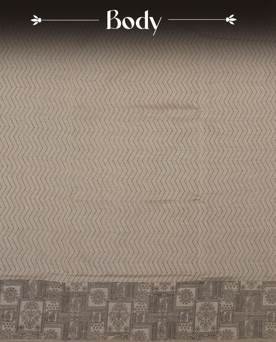 Dark Beige colour poly cotton saree with black zigzag line pattern on the body, paired with a matching pallu featuring black chevron lines and panelled floral‑paisley design, and a coordinated all‑over floral paisley patch‑style printed blouse piece.