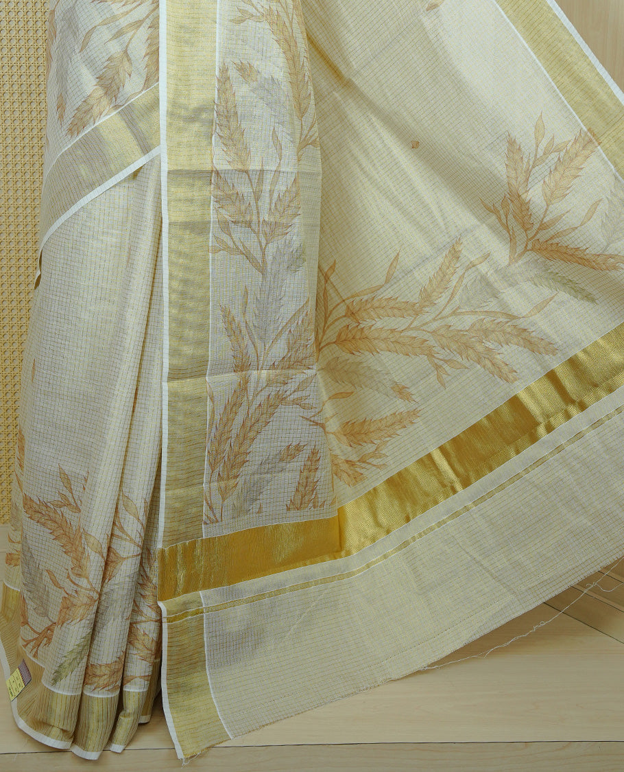 Light gold colour tissue Kerala saree featuring Leaf print & Gold zari check on body, complemented by gold Border, comes with matching blouse piece.