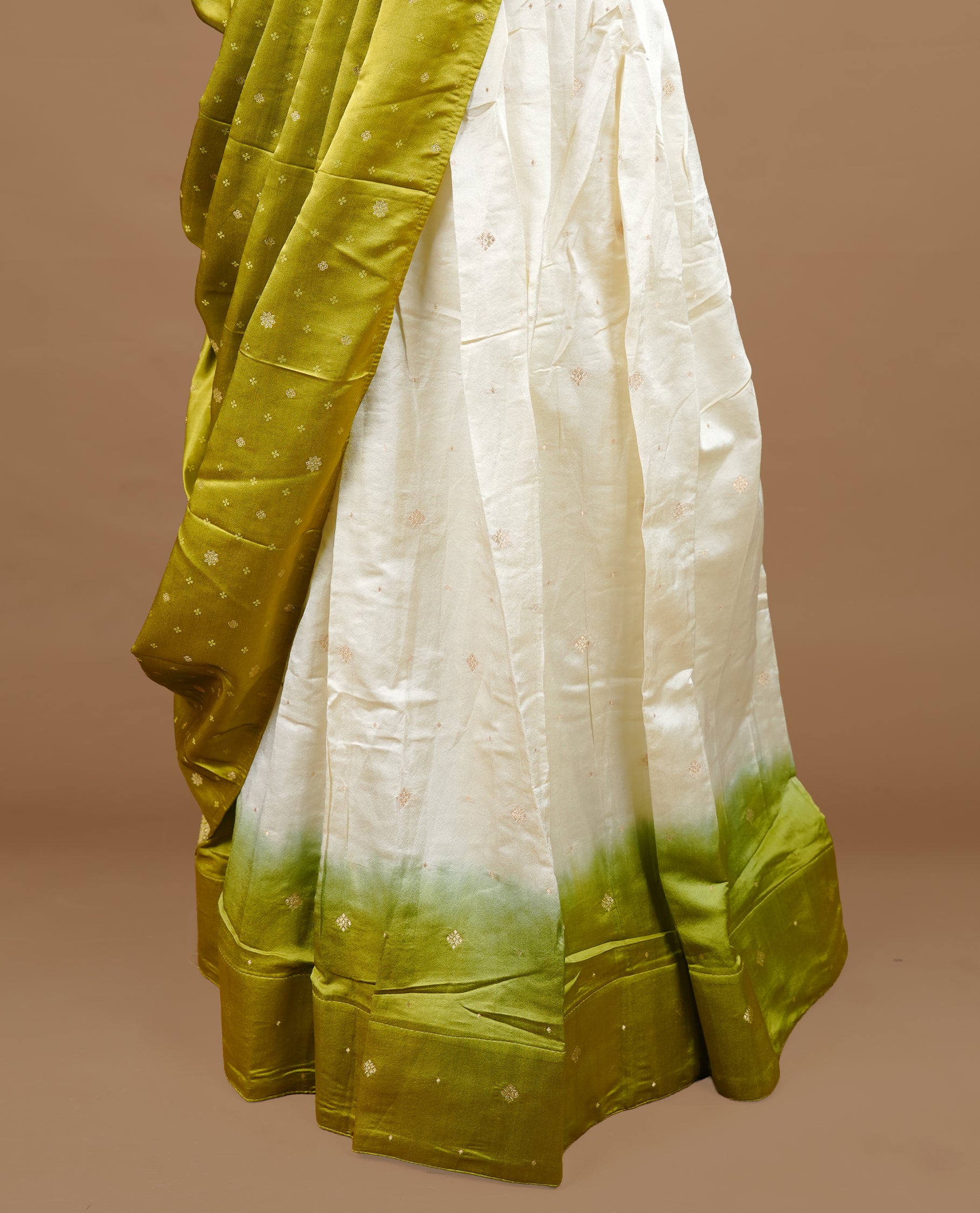 Off white colour semi stitched half saree featuring elegant zari buttas on the body, paired with a contrast pastel green border and matching striped dupatta,paired with matching blouse piece.