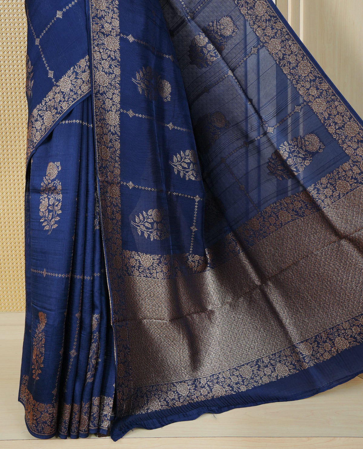 Navy blue colour semi banaras tussar georgette saree featuring gold zari floral pattern body, finished with gold zari floral motifs on border and paired with matching blouse piece.