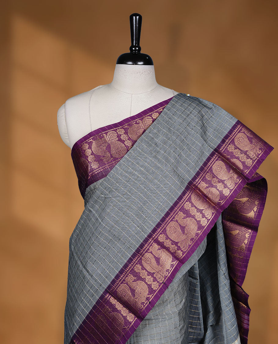 Grey colour sungudi cotton saree featuring gold zari check pattern across body, contrast Purple colour with gold zari peacock pattern on border, without blouse piece.