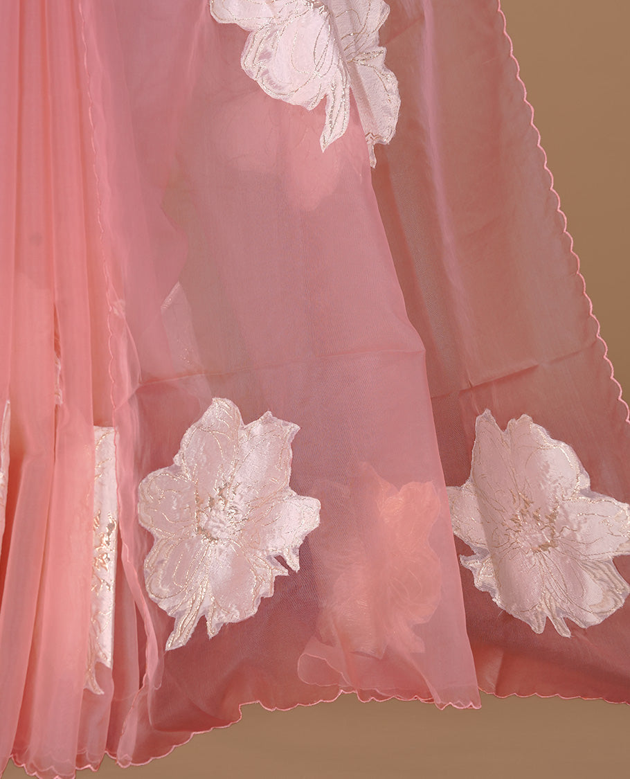 Pastel pink colour semi organza saree featuring white floral & gold thread pattern, highlighting scalp design border, paired with matching blouse piece.