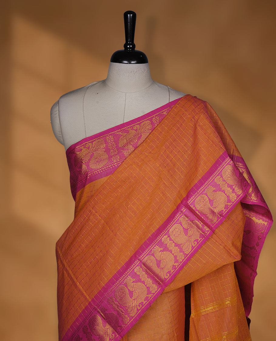 Orange colour chettinad cotton saree featuring gold zari check patterned body, contrast pink colour with traditional gold zari border paired without blouse.