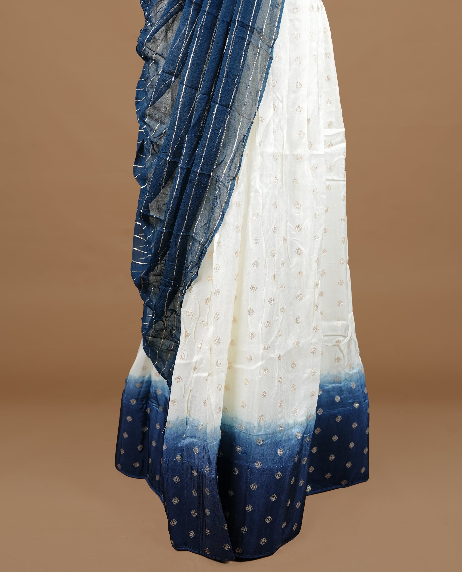 Off white colour semi stitched half saree featuring elegant zari buttas on the body, paired with a contrast blue border and matching motifs dupatta,paired with matching blouse piece.
