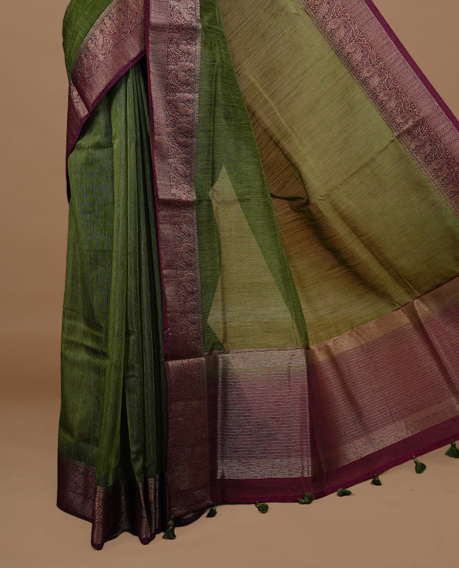 Olive green colour Semi linen saree featuring Elegant plain body, complemented by contrast Maroon colour With Antique zari border, paired with matching blouse piece.