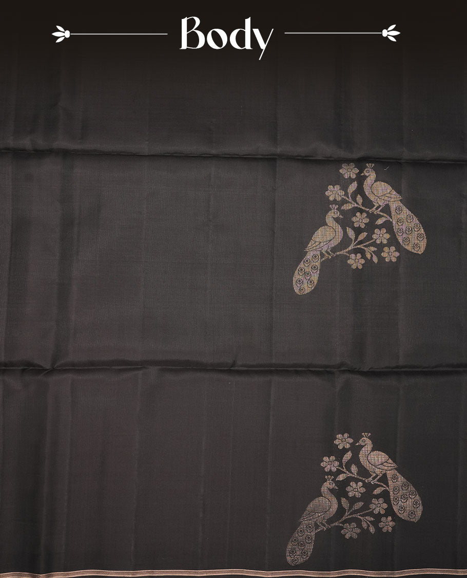 Black colour soft silk saree featuring gold zari peacock motifs on body, complemented by self colour with gold zari border, peacock print on pallu, paired with matching blouse piece.