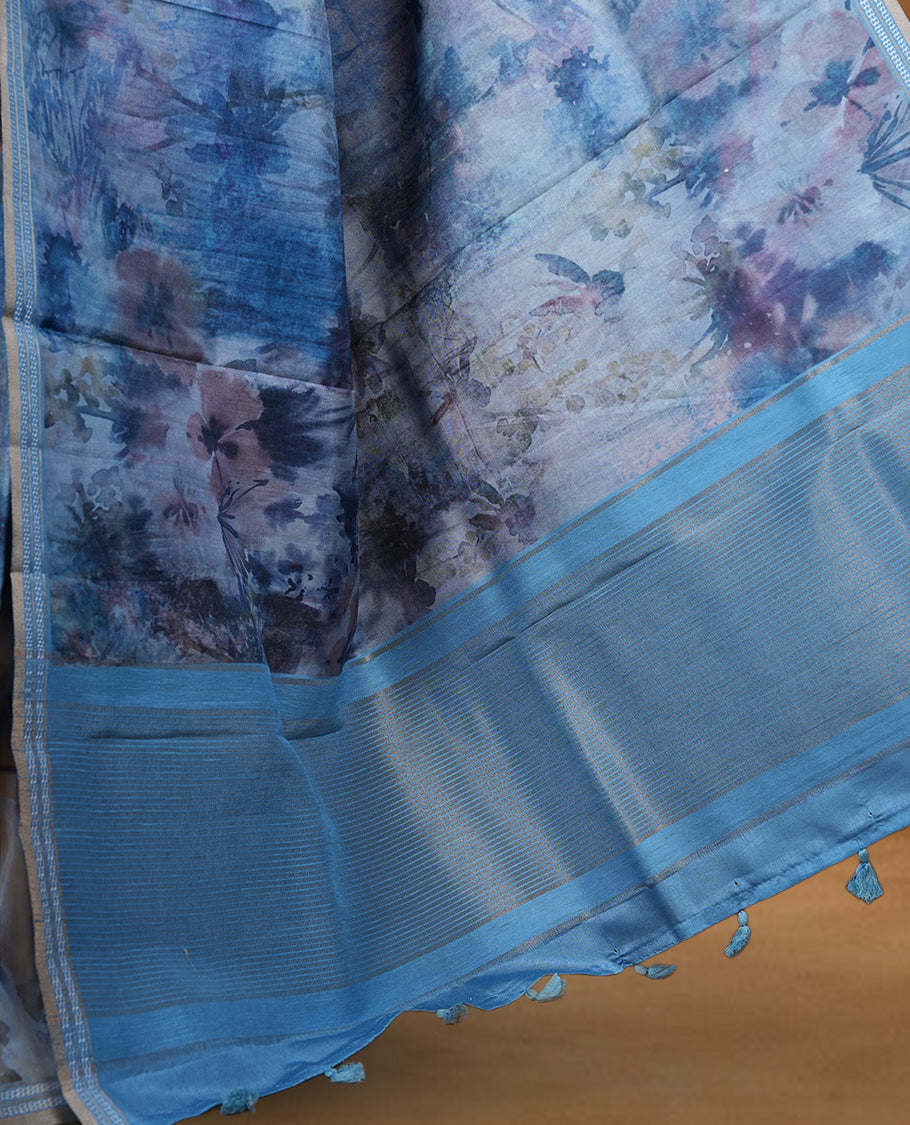 Ocean blue colour semi tussar silk saree featuring an abstract floral printed body with a rich self border and tasselled pallu, paired with a matching blouse.
