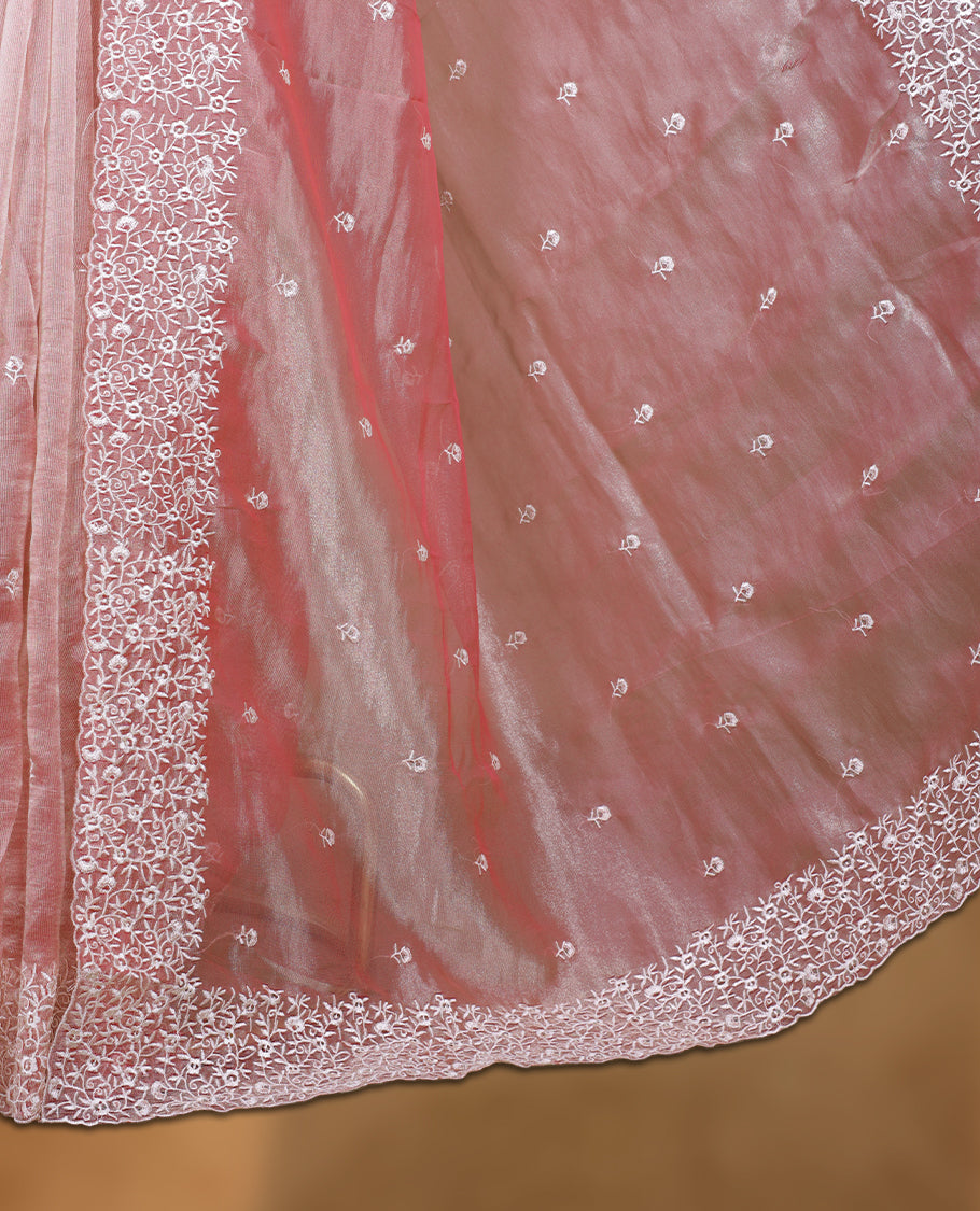 Peach colour net organza designer saree featuring a subtle self patterned body and an intricately scalloped floral thread embroidered border all around, complemented by a coordinating embroidered pallu and paired with a matching blouse.