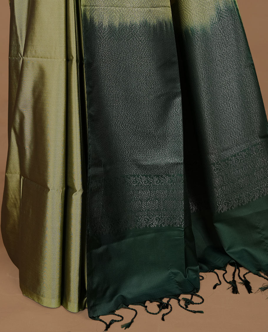 Olive colour soft silk saree features a sleek borderless design with intricate antique zari motifs, flowing into a striking contrast green pallu and a matching blouse piece.