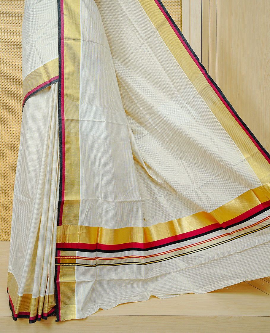 Cream colour cotton Kerala saree Featuring Gold zari Checks across the body, complemented by Classy Gold zari with an Maroon & Black Border & pallu, paired with a matching blouse piece.