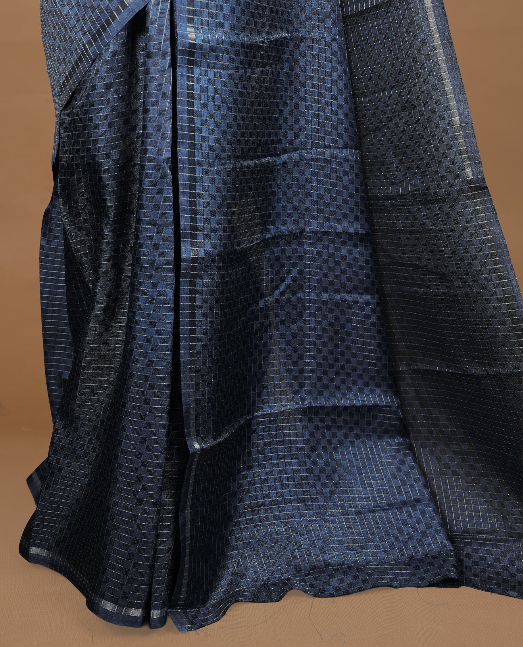 Navy Blue colour Semi Tussar saree featuring an elegant zari fancy check pattern on the body, highlighted with a small border for a refined look. Comes without a blouse piece.