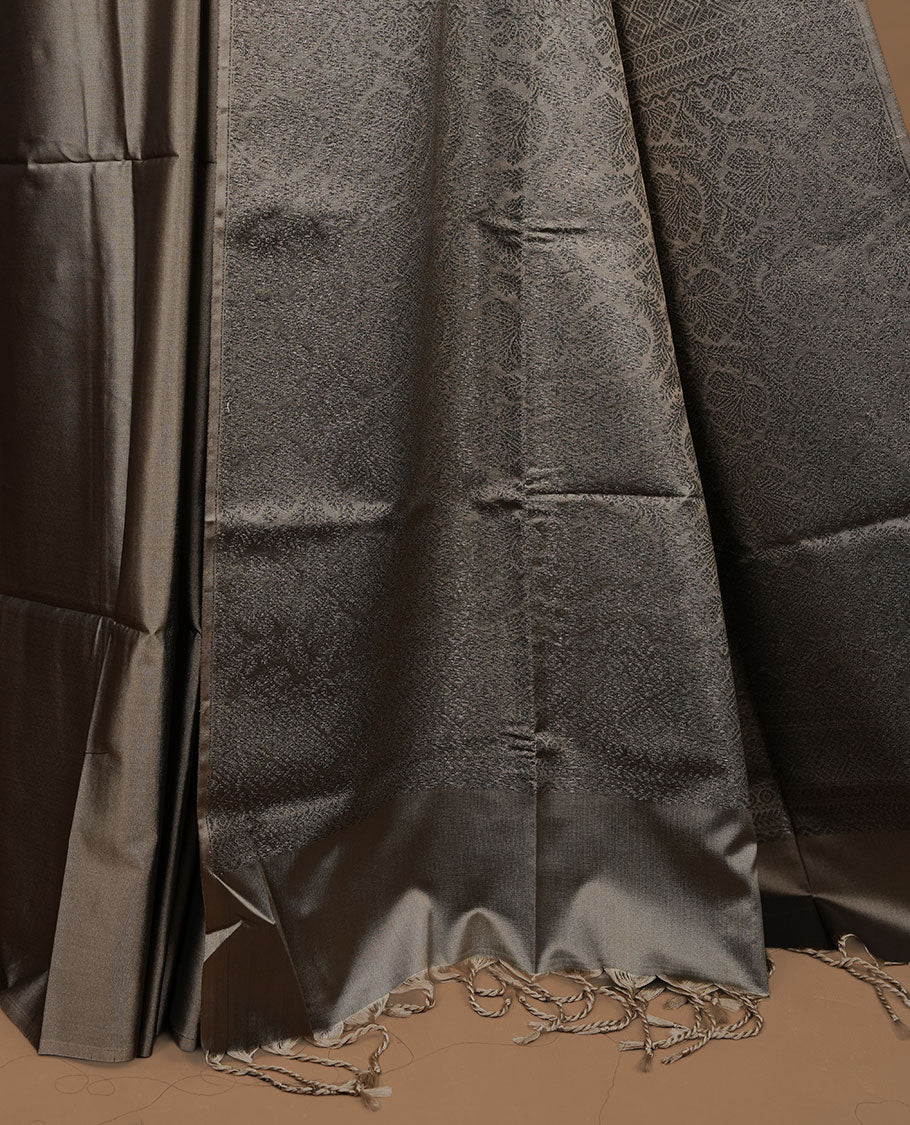 Greyish green soft silk saree features a sleek borderless design with intricate antique zari motifs, flowing into a seamless self colored pallu and a matching blouse piece.