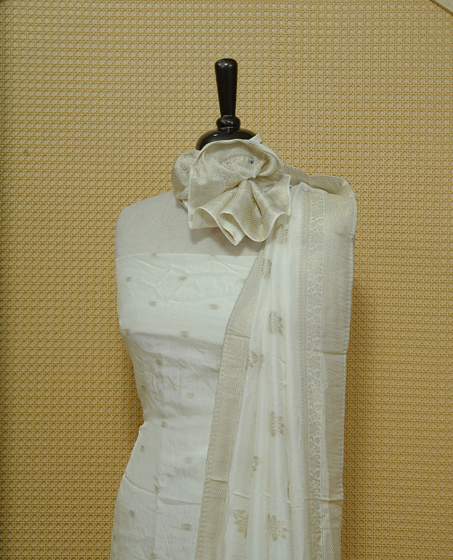 Cream colour Salwar material featuring gold zari Buttas on body, paired with matching dupatta & Bottom.