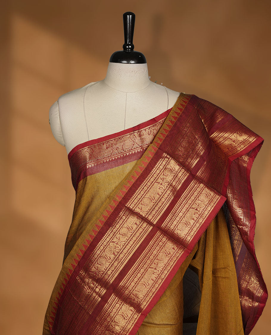 Mustard colour chettinad cotton saree featuring plain body, paired with a black colour traditional gold zari border paired with matching blouse.