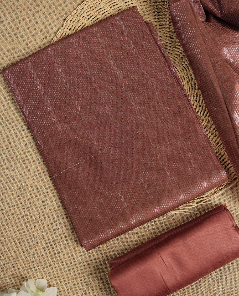 Pastel chocolate brown colour tussar suit material featuring a subtle self copper zari woven vertical and stripped pattern on the body, paired with a lightweight matching dupatta with tassel edges and a plain bottom piece.