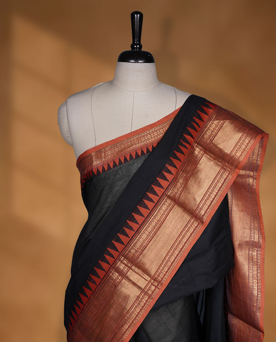Black colour chettinad cotton saree featuring Elegant plain body highlighting contrast orange colour colour with gold zari traditional border, pallu and paired with matching blouse piece.