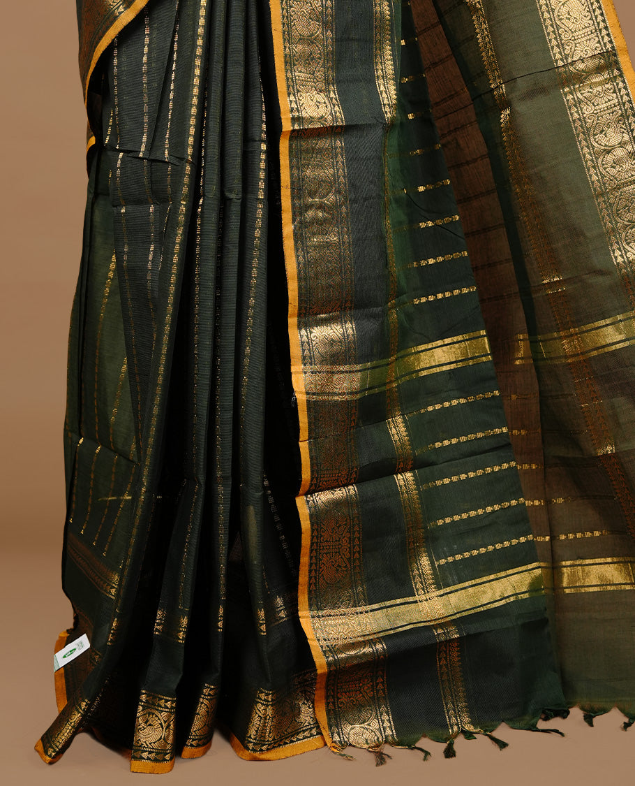 Dark green colour chettinad cotton saree featuring gold zari stripes on body, complemented by self colour with zari mustard piping border, paired with matching blouse piece.