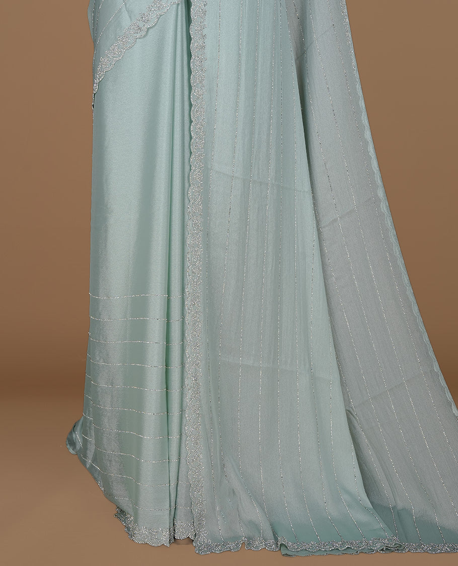 Light blue colour designer saree featuring white stone stripes on body, highlighting white stone with scalp border, paired with matching blouse piece.