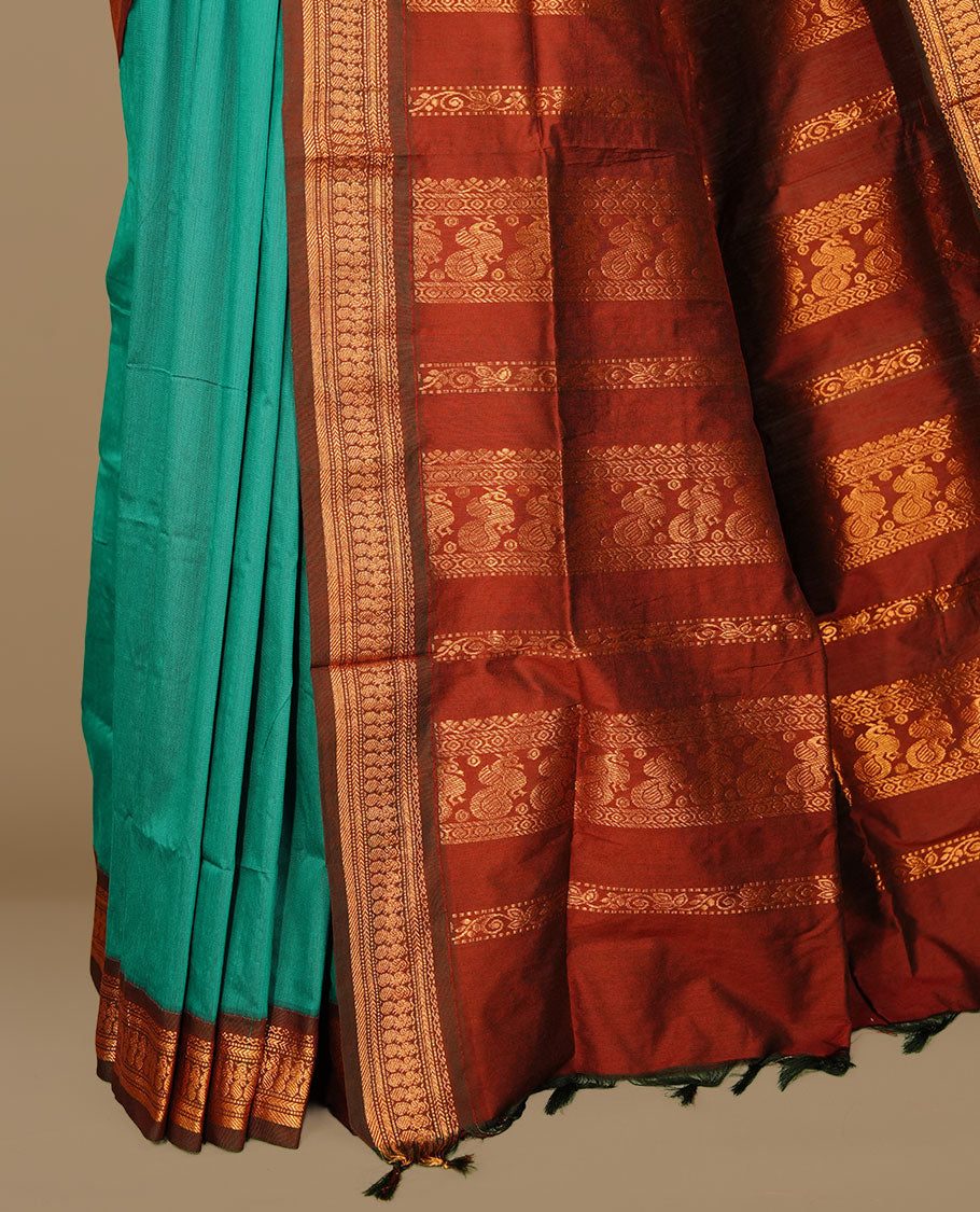 Teal colour kalyani cotton saree featuring antique zari motifs on body, complemented by Maroon colour with Antique zari border, paired with matching blouse piece.
