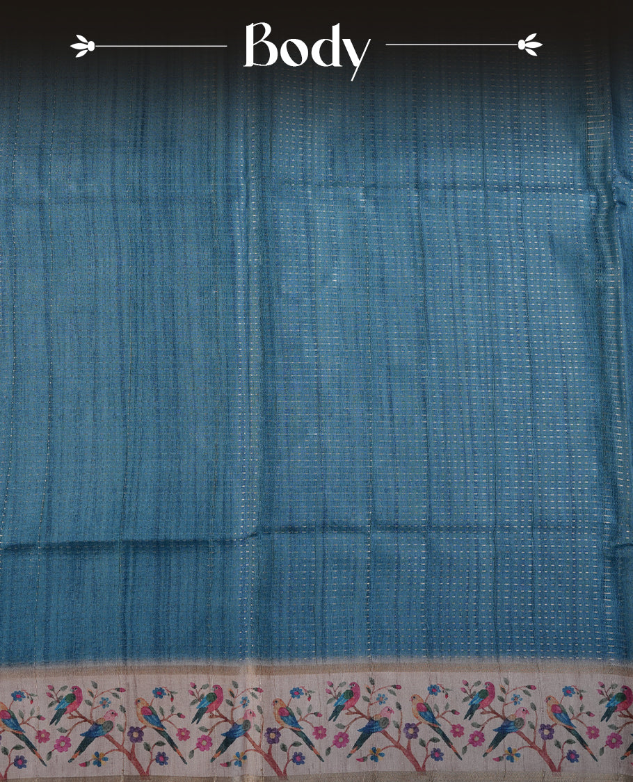 Teal colour tussar saree featuring golden zari dot stripped pattern on the body, complemented by a contrast cream colour mutlicolour floral kodi & animal print on border & pallu, paired with a matching blouse.